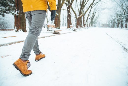 Man walking in the snow through a park